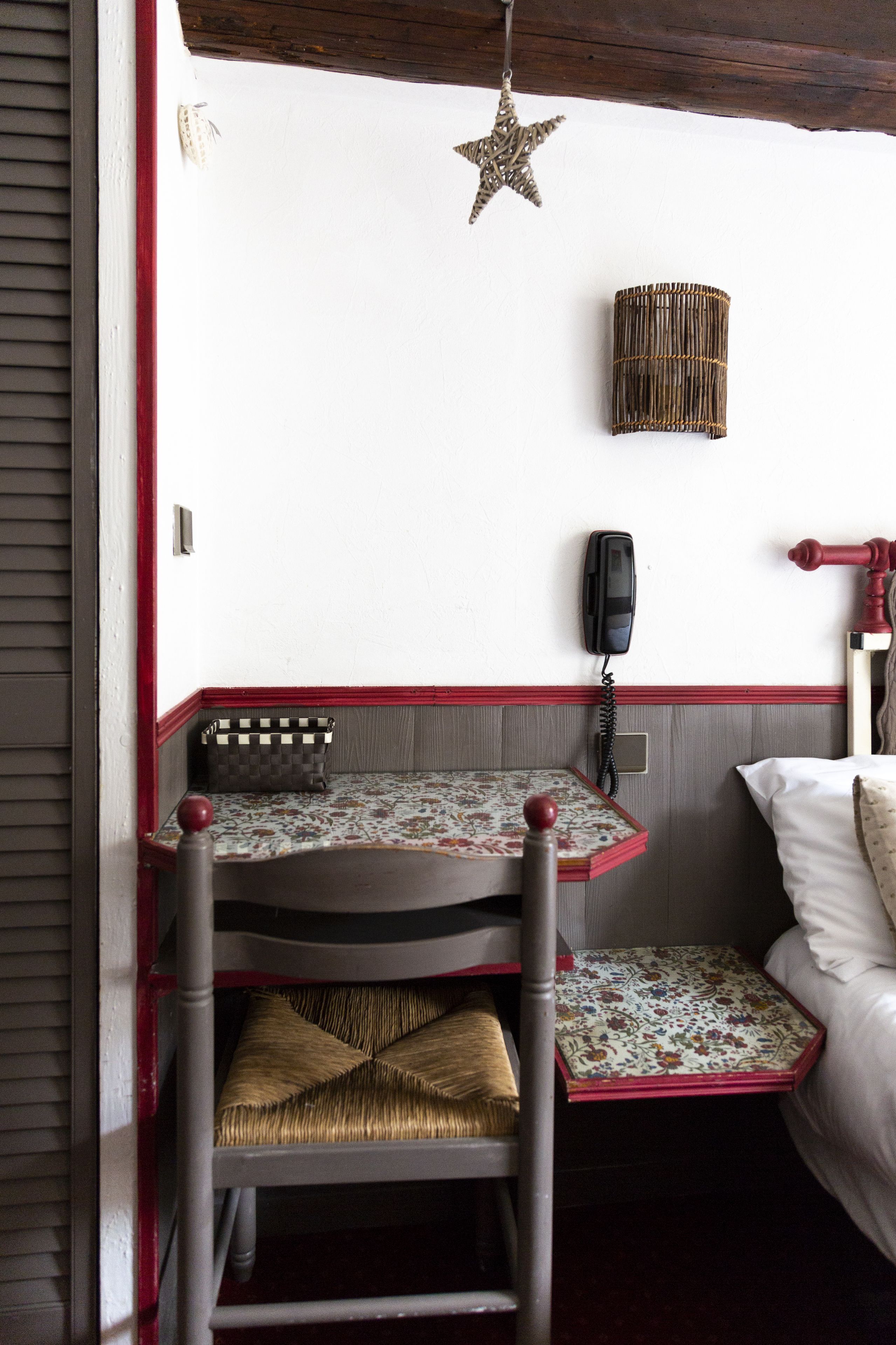 A corner room with a wooden chair, a small table, a telephone, and a decorative star hanging from the ceiling.