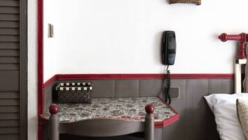 A corner room with a wooden chair, a small table, a telephone, and a decorative star hanging from the ceiling.