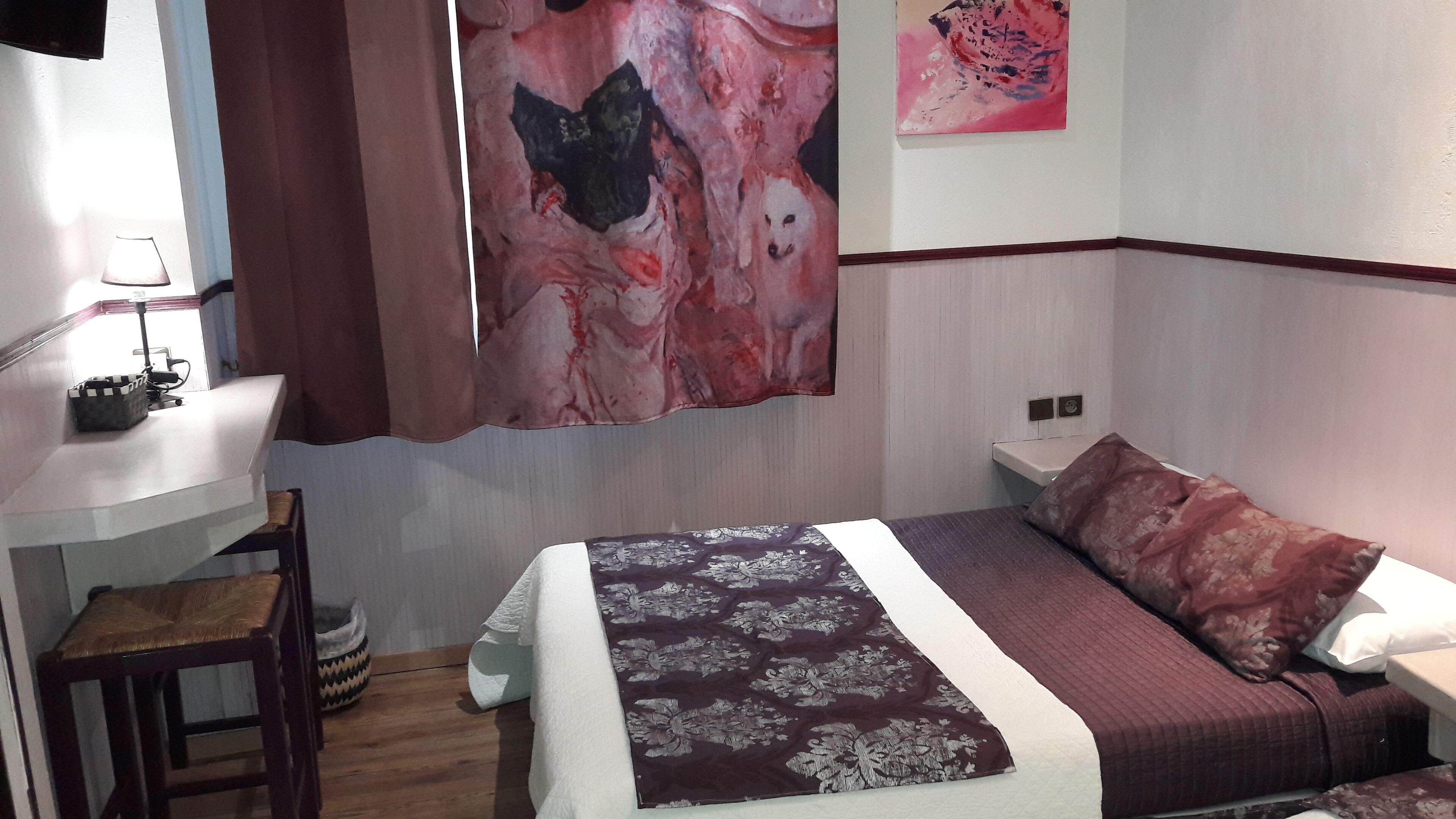 Ein Schlafzimmer mit einem Bett, einem Schreibtisch, einem Stuhl und einem großen abstrakten Gemälde an der Wand.