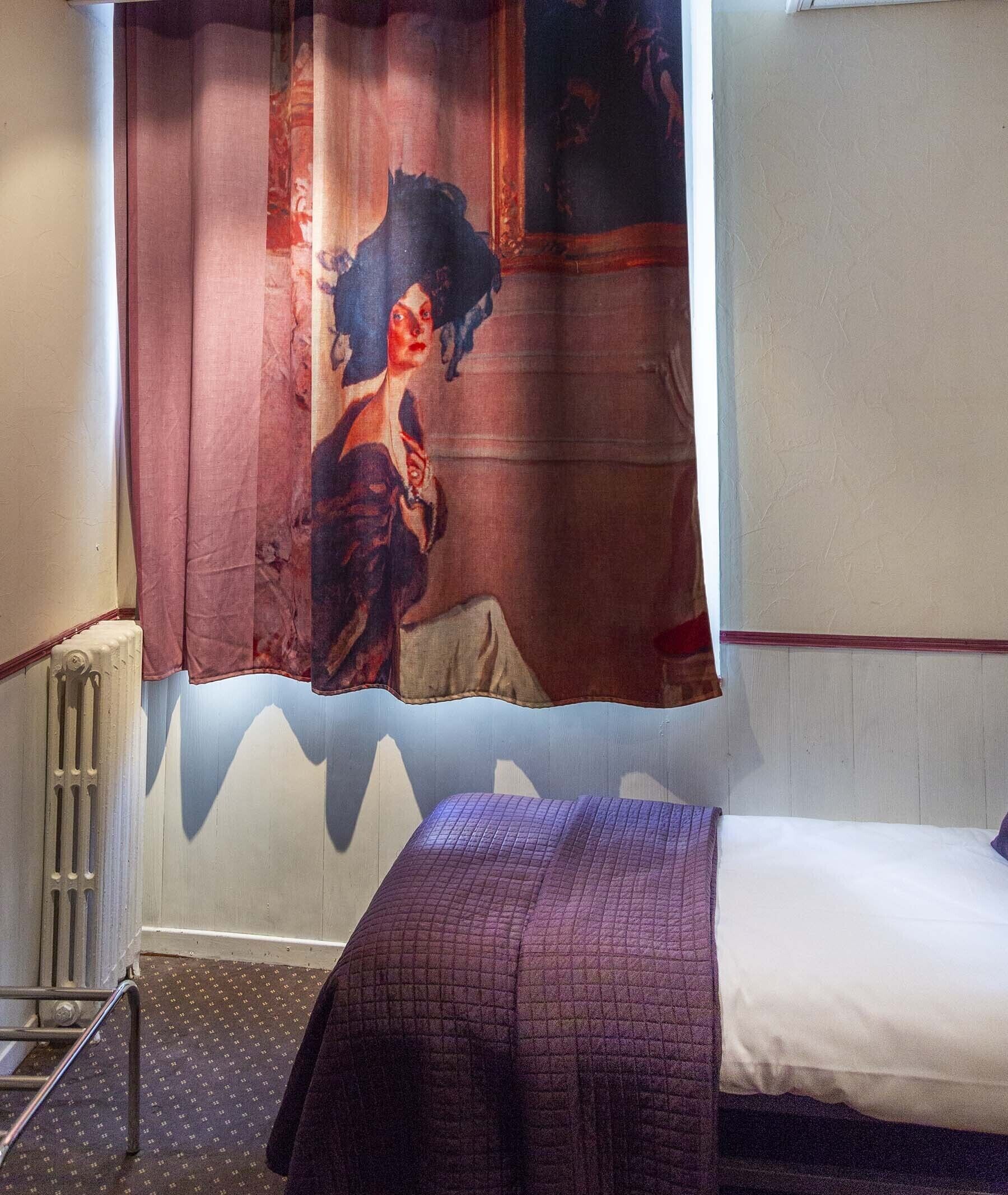 Une chambre à coucher avec un lit, un radiateur, un rideau et un mur orné d’un motif texturé.