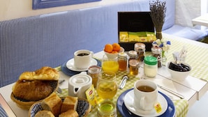 Una mesa de desayuno con cruasanes, pan, jugo de naranja, café, té y una variedad de aderezos.