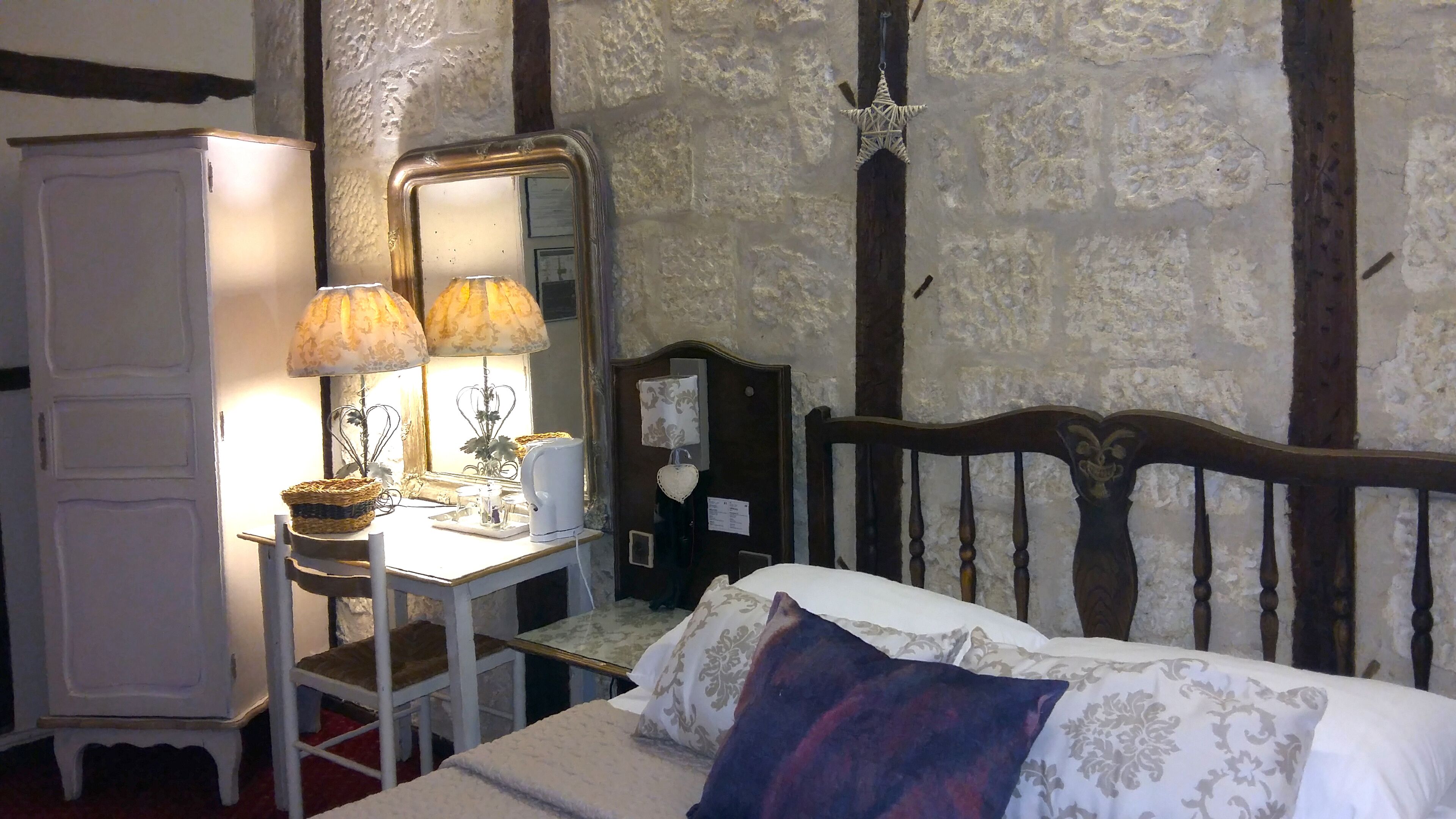 Un dormitorio con cama, cómoda, espejo y lámpara.
