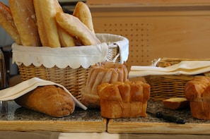 A basket of baguettes and croissants on a countertop. - Hôtel Les Vallées (La Bresse)