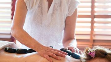 A person receiving a back massage with hot stones.