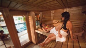 A wooden sauna with two people relaxing on benches. - Hôtel Les Vallées (La Bresse)