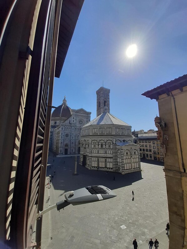 A historic square with a prominent building featuring a dome and a tower.
