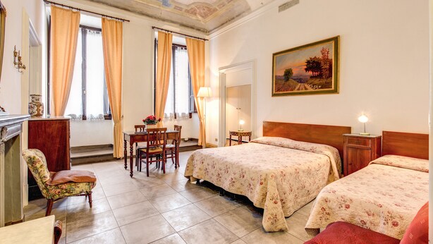 Una habitación de hotel con dos camas, una zona de comedor y un cuadro en la pared.