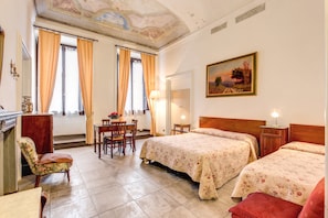 A hotel room with two beds, a dining area, and a painting on the wall. - Hotel San Giovanni (Florence)