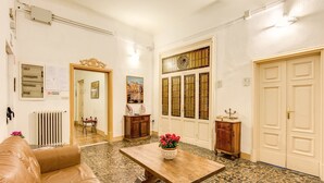 Amplia sala de estar con un sofá de cuero, una mesa de centro de madera con un florero y piso de baldosas.