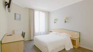 Een hotelkamer met een bed, nachtkastjes, een bureau, een stoel, een raam met gordijnen en een schilderij aan de muur.