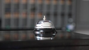 Een hotelkamer met een spiegelende oppervlakte en een bel op een tafeltje.