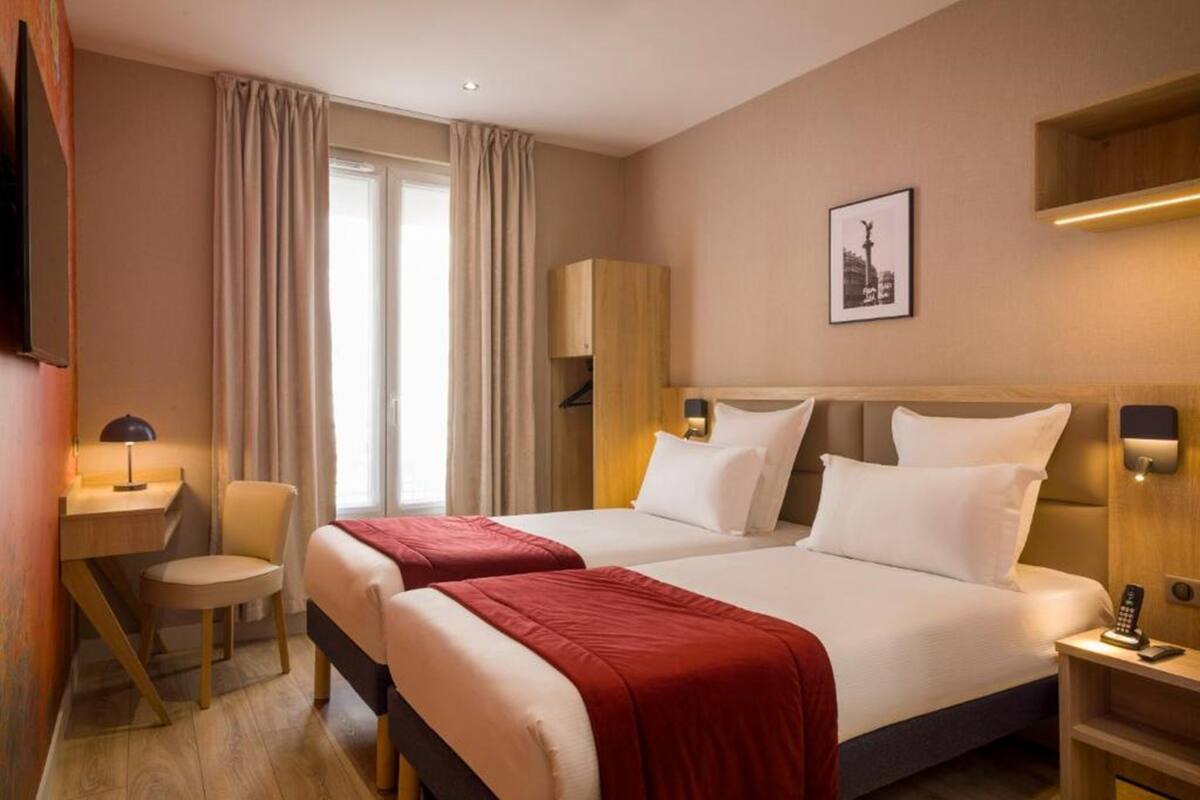 A hotel room with two beds, a desk, a chair, a TV, and a picture on the wall.