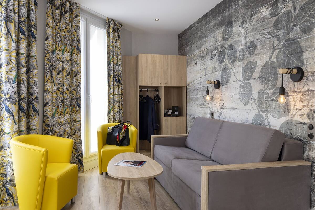 A modern room with a sofa, two yellow chairs, a small table, and a wardrobe.