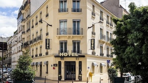 Un hotel en esquina con varios balcones, una entrada destacada y un letrero que indica que es un hotel.