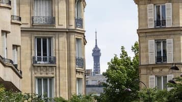 Visão de um edifício com várias varandas e janelas, e uma torre ao fundo.