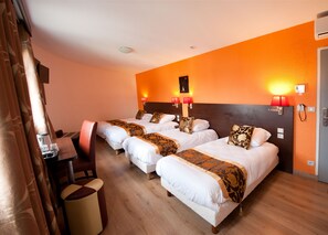 A hotel room with three beds, wooden flooring, a desk with a chair, and a small trash bin. - Hotel Milton (ex Gis Hotel) (Neuilly-Plaisance)