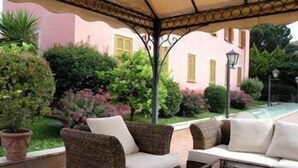 An outdoor seating area with wicker furniture and a pergola. - Arco di Travertino (Rome)