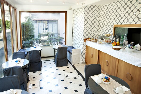 A dining area with tables and chairs, a buffet with food and drinks, and a view of the outside. - Arco di Travertino (Rome)
