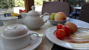 A table with a teapot, a bowl of fruit, and a plate with eggs and tomatoes. - Arco di Travertino (Rome)