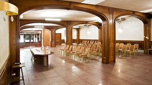 A spacious hall with a long table and rows of chairs, wooden arches, and a tiled floor. - Arco di Travertino (Rome)