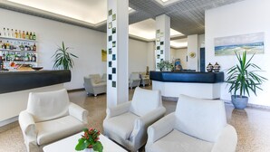 A lobby with a reception desk, seating area, and a bar with shelves of bottles. - Alba d'Oro (Bellaria-Igea Marina)