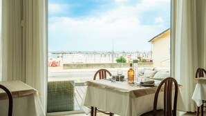 A dining area with a table set for two, overlooking a beach and the sea. - Alba d'Oro (Bellaria-Igea Marina)