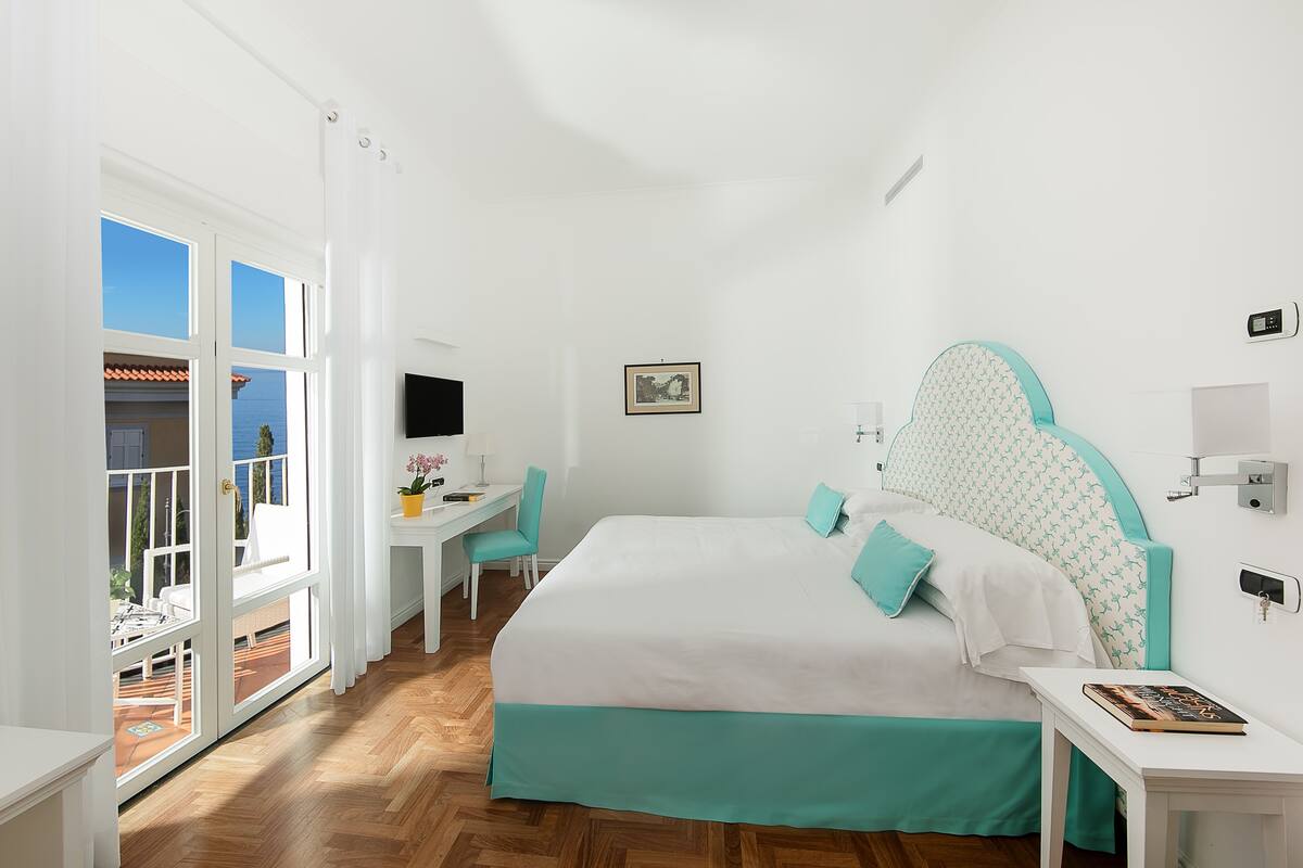 A bedroom with a large bed, a desk, and a chair.