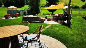 An outdoor patio area with a wooden table, wicker chairs, and a sofa set under a yellow canopy.