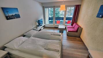 Habitación de hotel con dos camas, televisión, una mesita y un sofá.