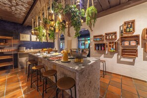 A bar area with a marble countertop, hanging plants, and wooden shelves with bottles. - Hotel Säntis Lodge (Wildhaus-Alt St. Johann)
