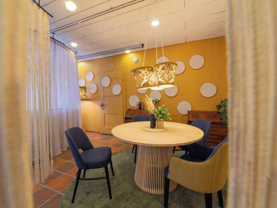 A dining area with a round table, blue chairs, and a decorative hanging light fixture.