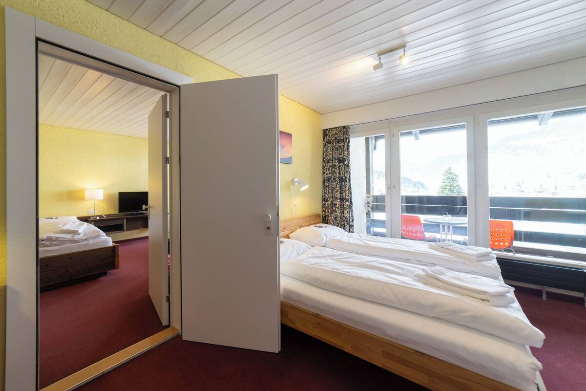 Ein Hotelzimmer mit Bett, Fernseher, Schreibtisch und einem Fenster mit Blick.