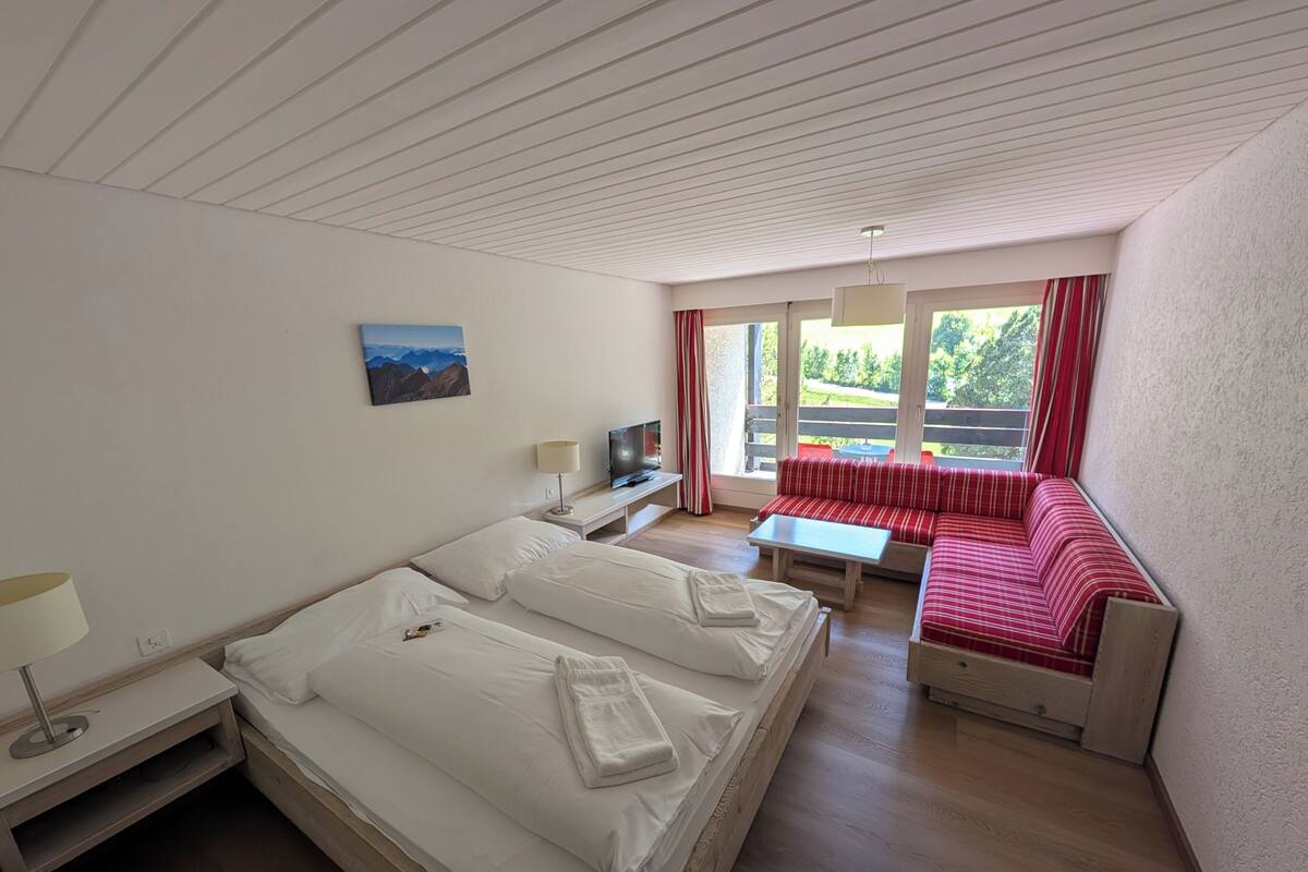 Ein Hotelzimmer mit Bett, Fernseher, Sofa und einem Balkon mit Blick.