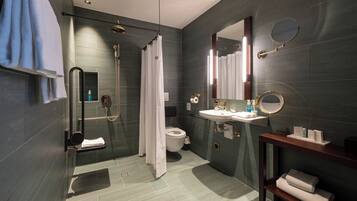 A modern bathroom with a shower, toilet, sink, and a mirror.