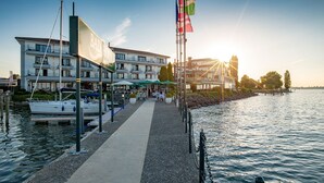 Un hotel frente al agua con muelle, asientos exteriores y exhibición de banderas.