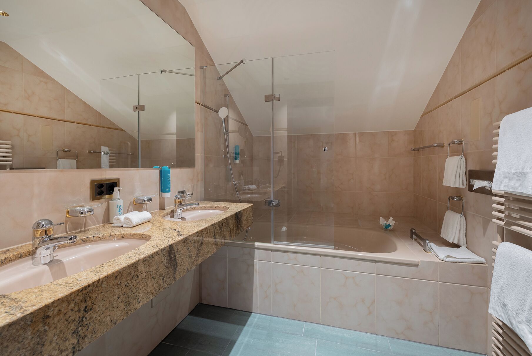 A modern bathroom with two sinks, a bathtub, and a shower.