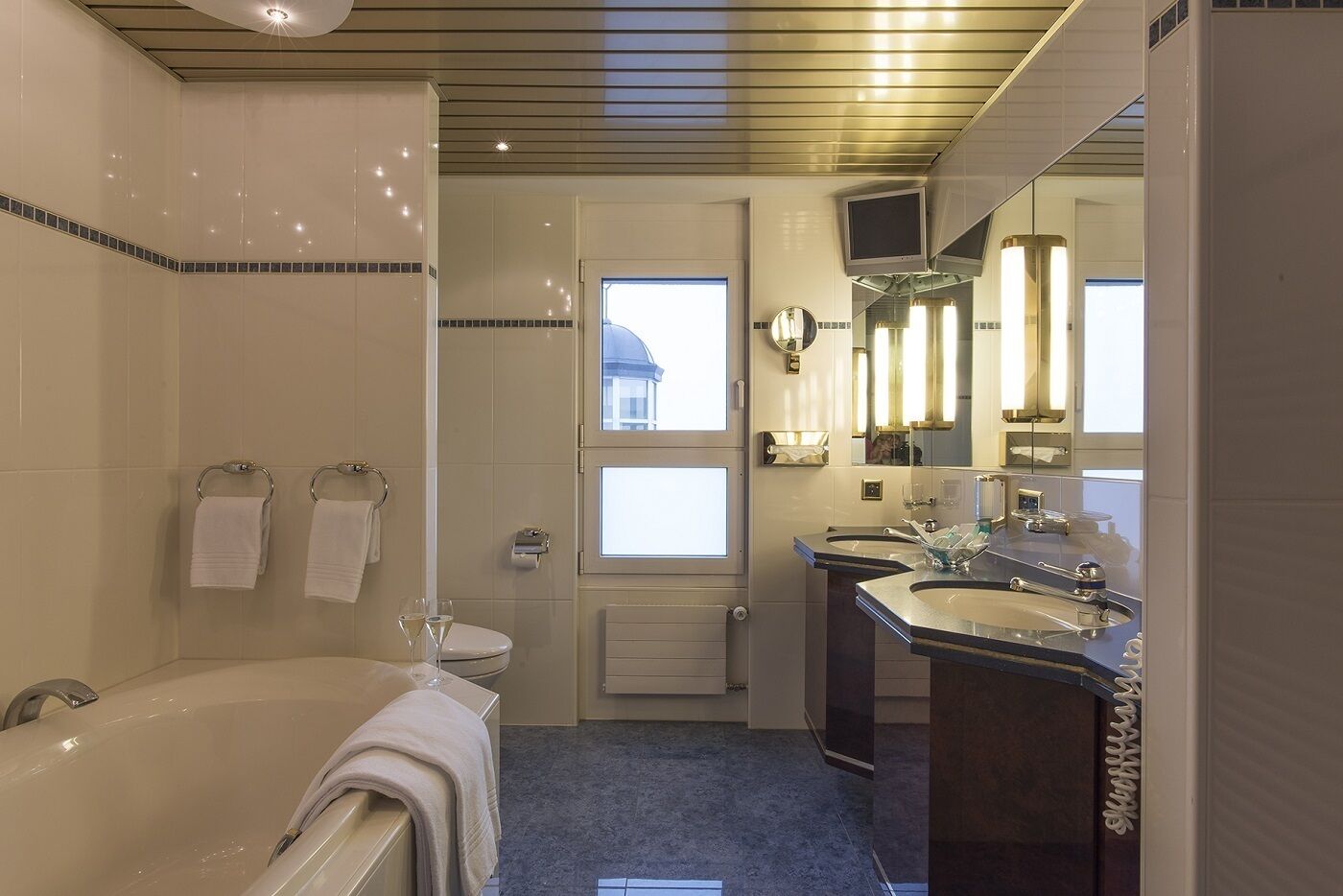 A modern bathroom with a bathtub, two sinks, a toilet, and a shower.