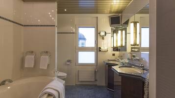 A modern bathroom with a bathtub, two sinks, a toilet, and a shower.