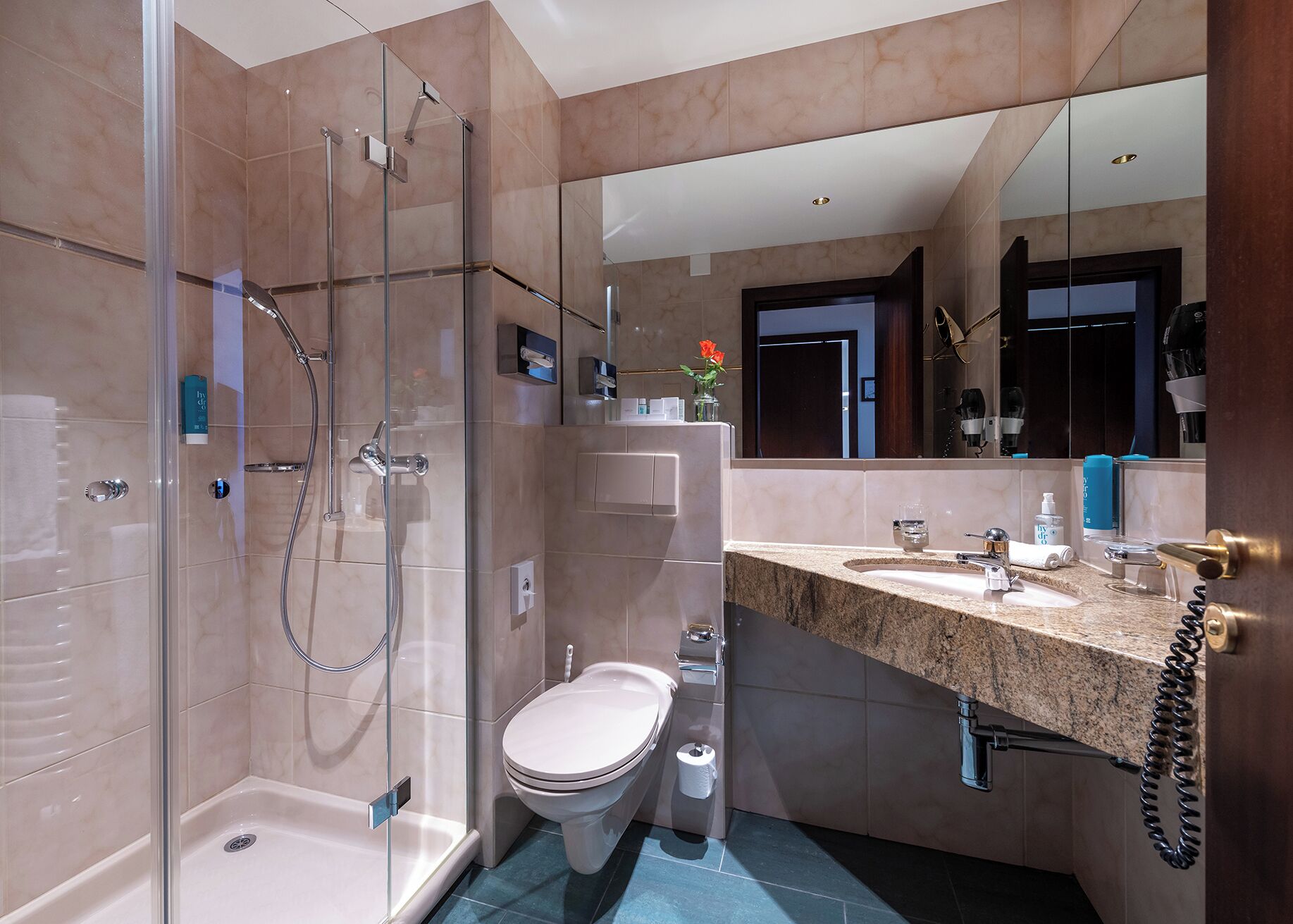 Une salle de bain moderne avec une douche à parois de verre, des toilettes et un meuble-lavabo avec un évier et un miroir.