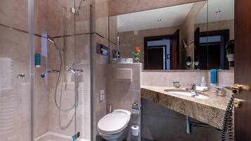 Une salle de bain moderne avec une douche à parois de verre, des toilettes et un meuble-lavabo avec un évier et un miroir.