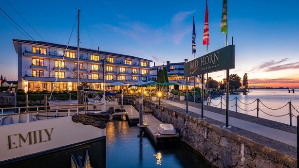 Un hotel frente al agua con muelle, barcos y un muro de piedra.
