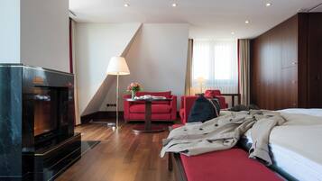 Une chambre d’hôtel avec un lit, un canapé rouge, une petite table avec une lampe et un téléviseur.