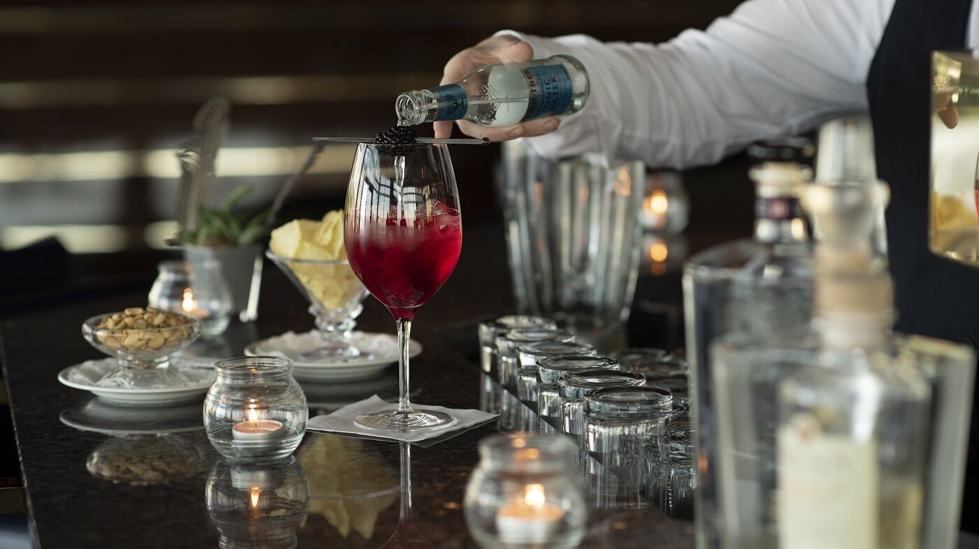 A bartender pouring a drink into a glass.