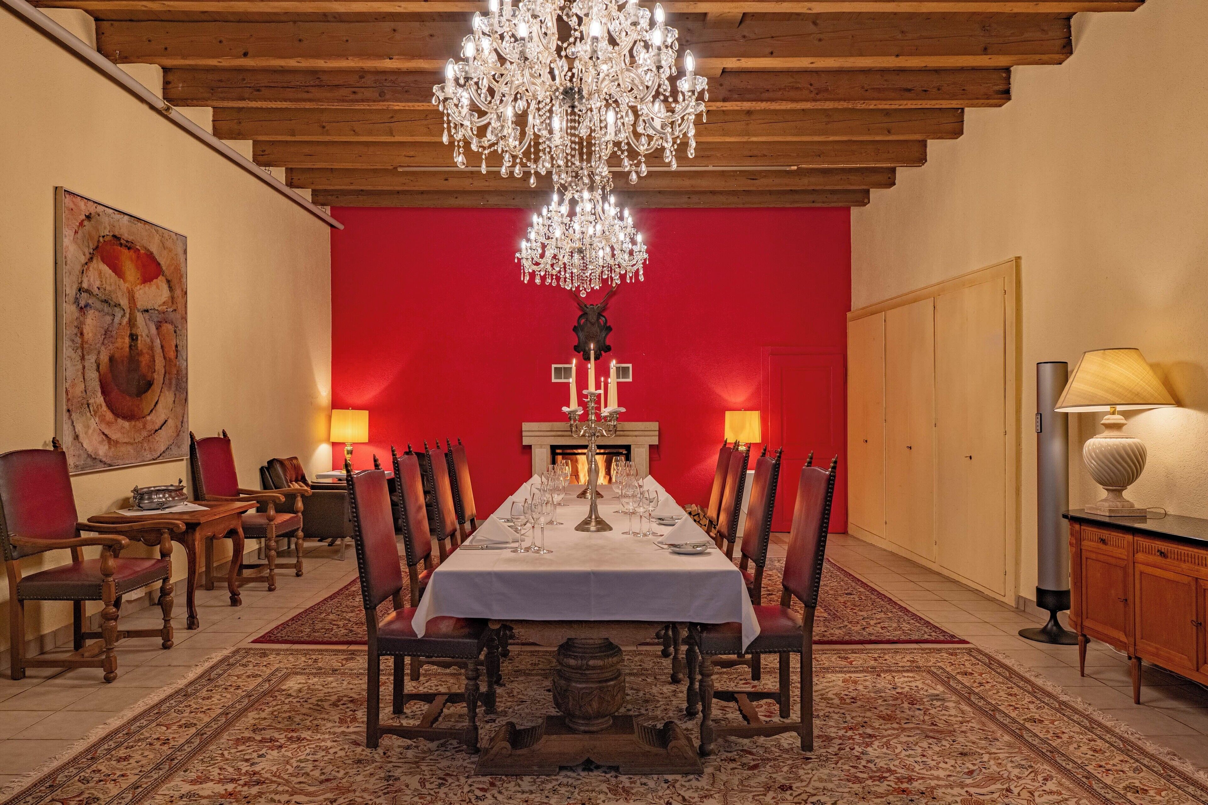Un comedor formal con una larga mesa, sillas, un candelabro y una chimenea.