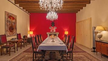 Un comedor formal con una larga mesa, sillas, un candelabro y una chimenea.