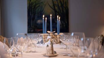 Una mesa de comedor dispuesta con varias copas de vino, un candelabro con velas encendidas y un cuadro al fondo.