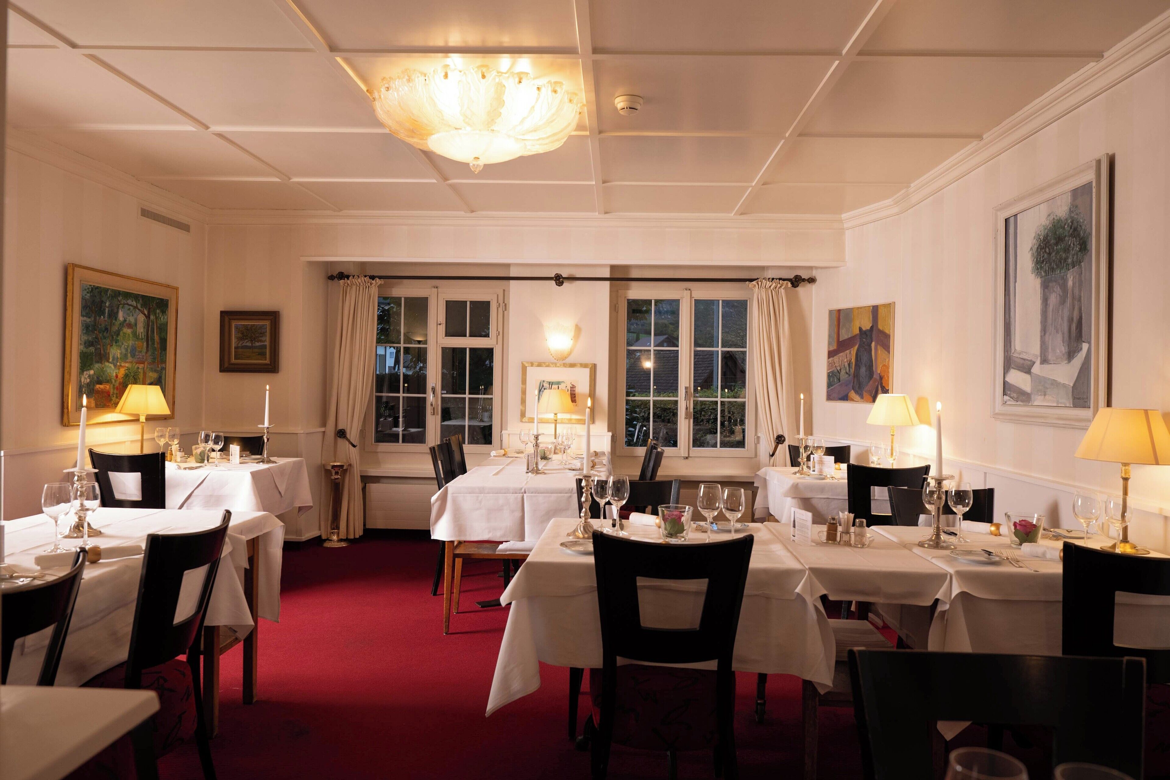 A dining area with tables set for four, each with candles and table settings.