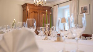 A dining table set with glassware and candles, a chandelier, and a wooden cabinet in the background. - Bad Eptingen (Eptingen)