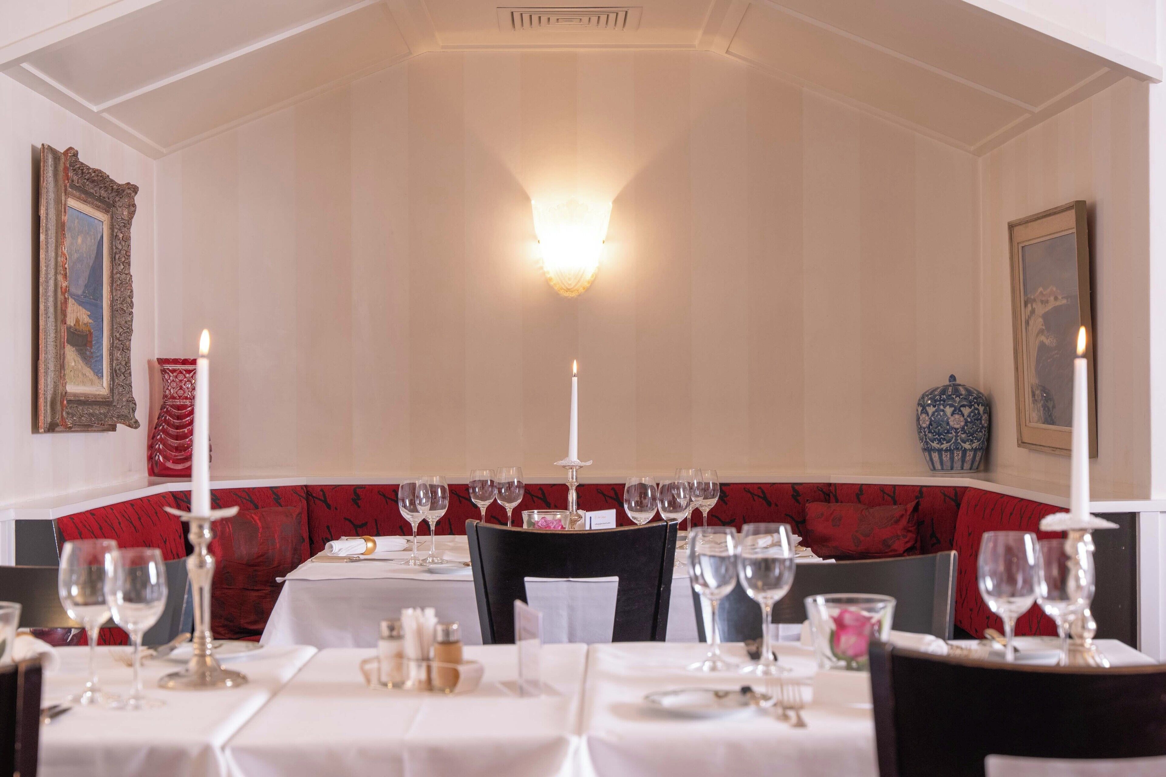 Un espace repas avec des tables dressées pour le dîner, agrémenté de nappes blanches, de bougies et de verres à vin.