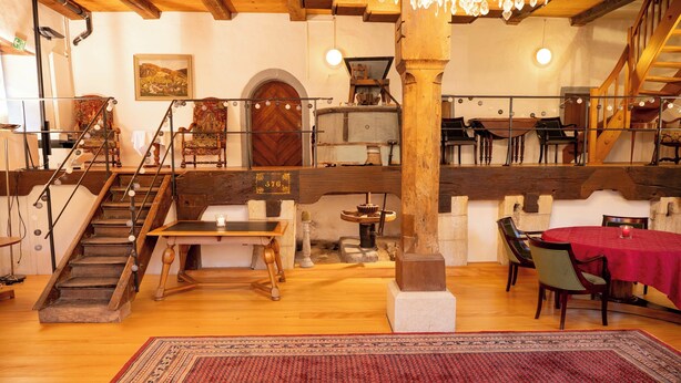 A rustic interior with a wooden staircase, a dining area with a red tablecloth, and a large rug. - Bad Eptingen (Eptingen)